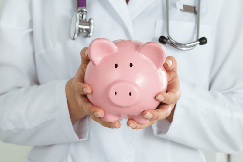 Doctor holding piggy bank to represent healthcare savings