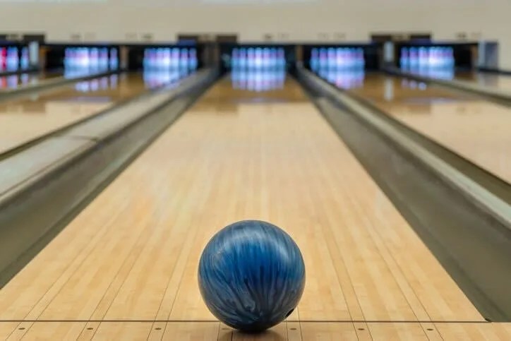 A blue bowling ball sitting in front of a bowling alley.
