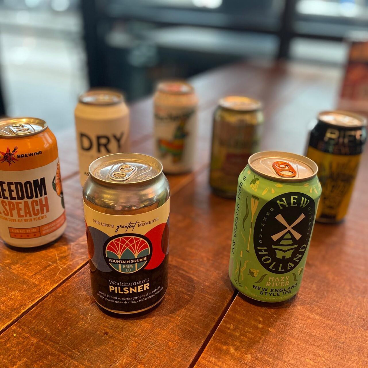 Colorful canned beers sitting on a wooden table.