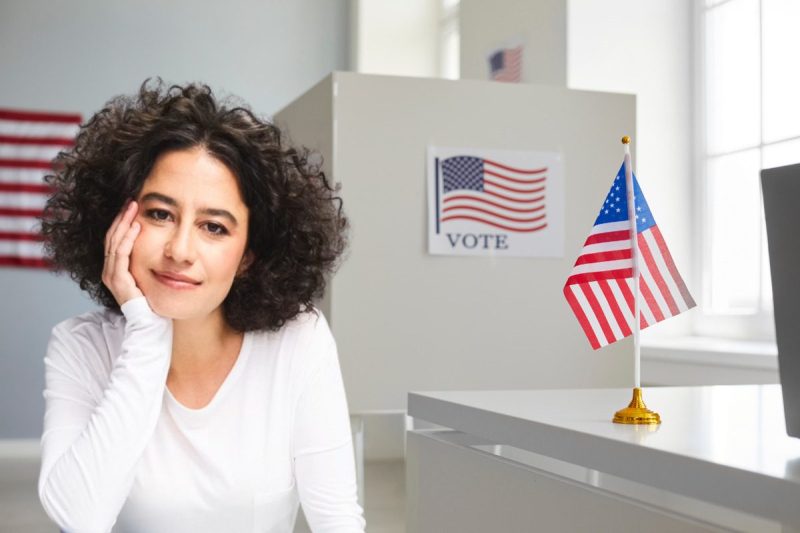 Opinion: I’m anti-war and voting for Harris and Walz, with faith in Gen Z & Millennials - Ilana Glazer infront of Empty polling station with white voting booths and American flag. Elections in the United States.