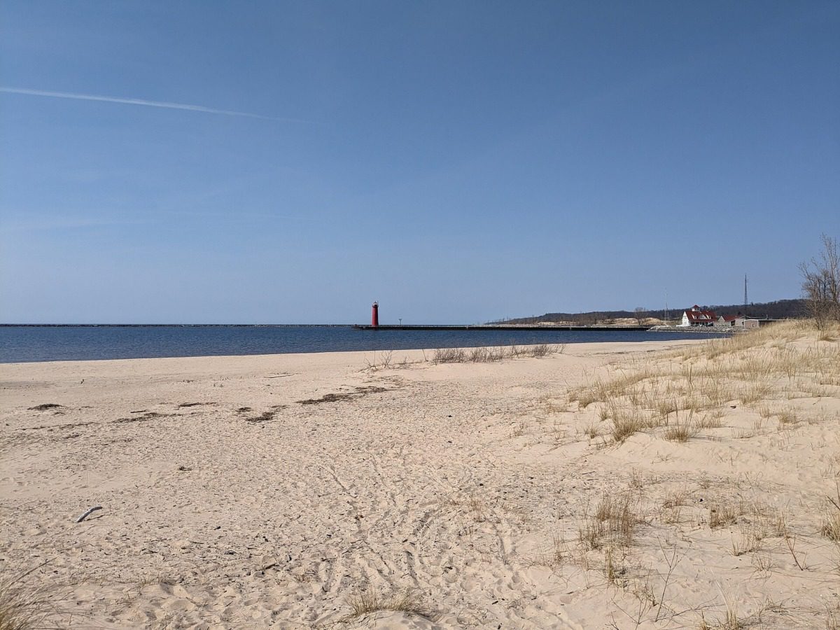 A view of the Pere Marquette Beach with a lighthouse in the background.