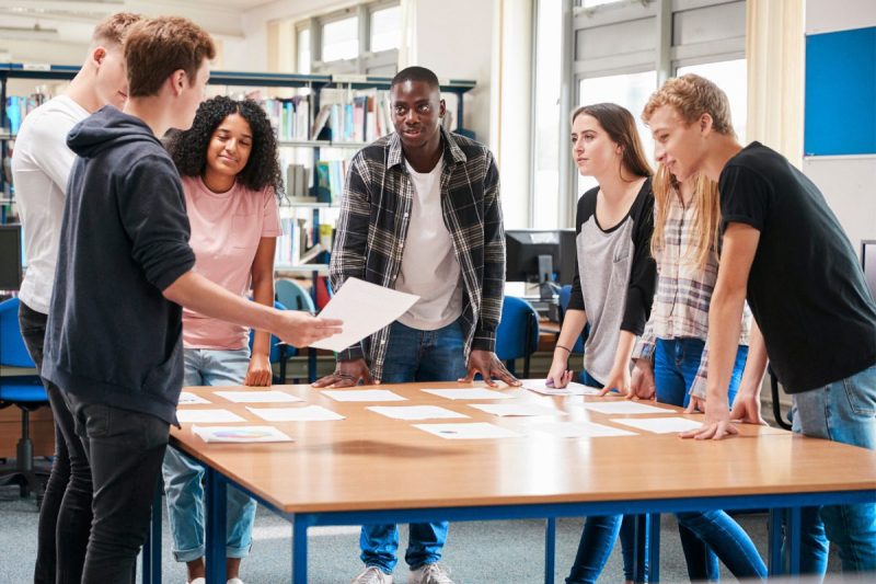 young people making plan, standing around table