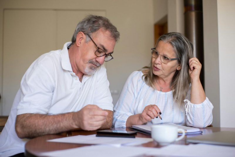 Photo of couple sitting at table discussing bills.