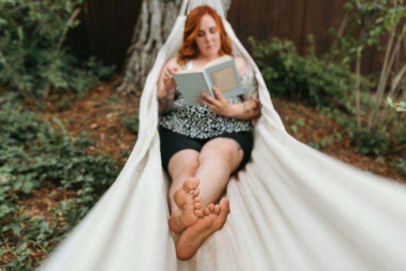 a woman reading a book in a hammock outside
