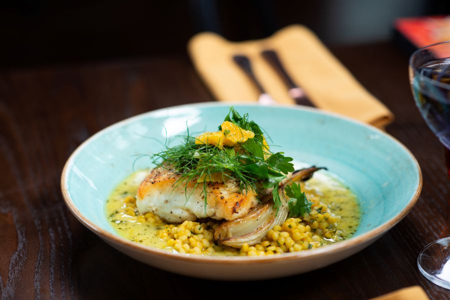 A bowl with fish and rice and a fancy green garnish